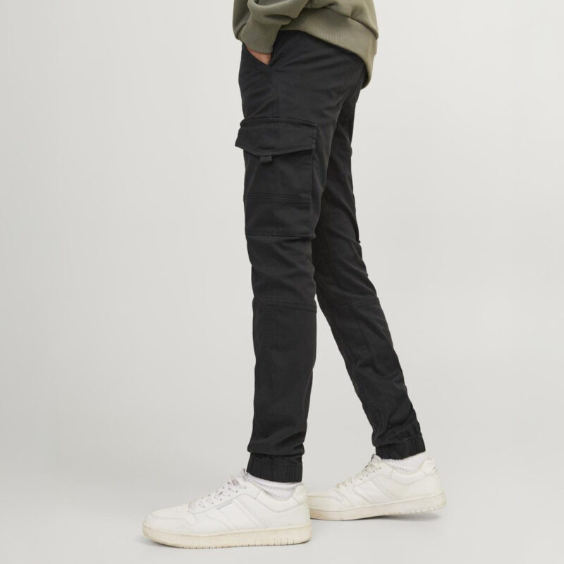 Ein junger Mann trägt schwarze Cargo-Hosen und weiße Sneakers.