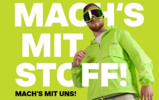 Ein Mann in einer leuchtend grünen Jacke trägt eine Skibrille vor einem grünen Hintergrund. Der Text "MACH'S MIT STOFF!" und "MACH'S MIT UNS!" ist prominent platziert.