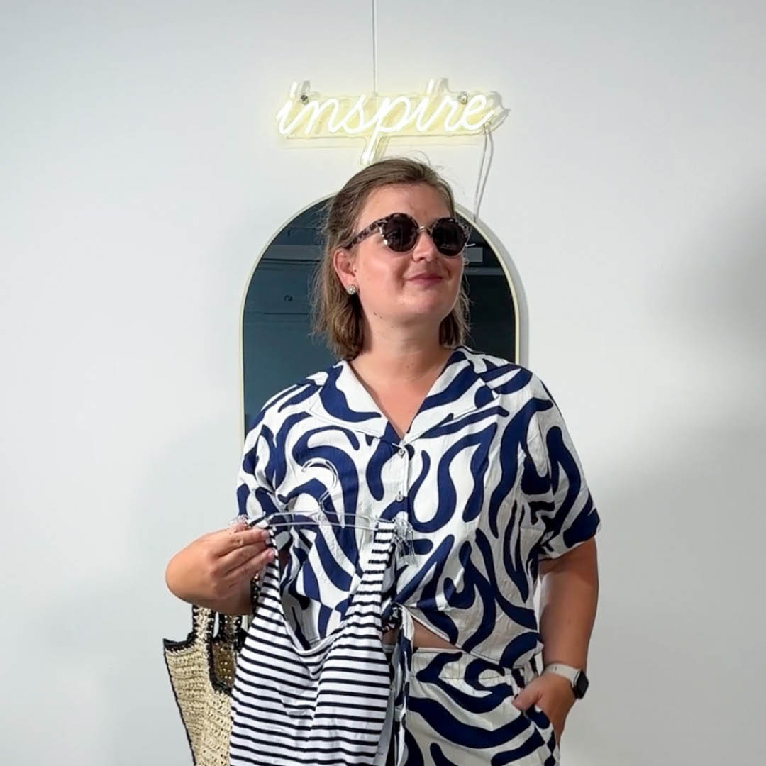 Eine Frau in einem blau-weißen Kleid hält eine Tasche in der Hand.