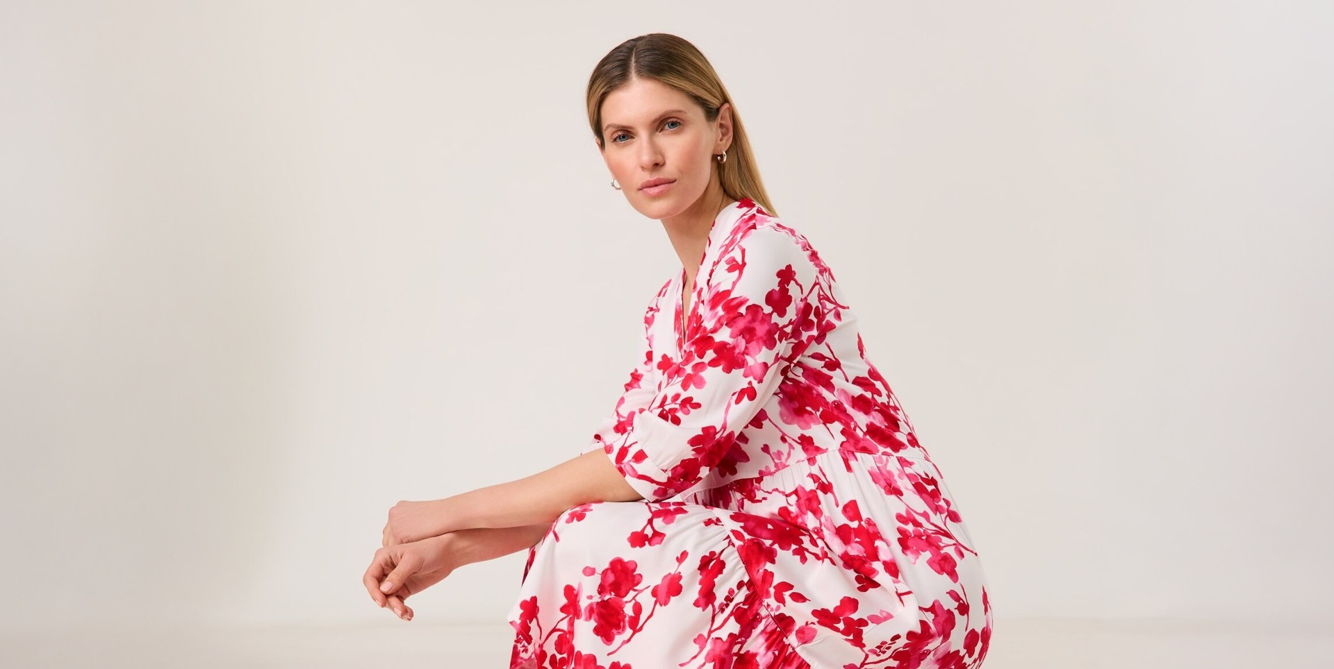 Eine Frau in einem rot-weißen Blumenkleid sitzt auf dem Boden. Eine Frau in einem rot-weißen Blumenkleid sitzt auf dem Boden.
