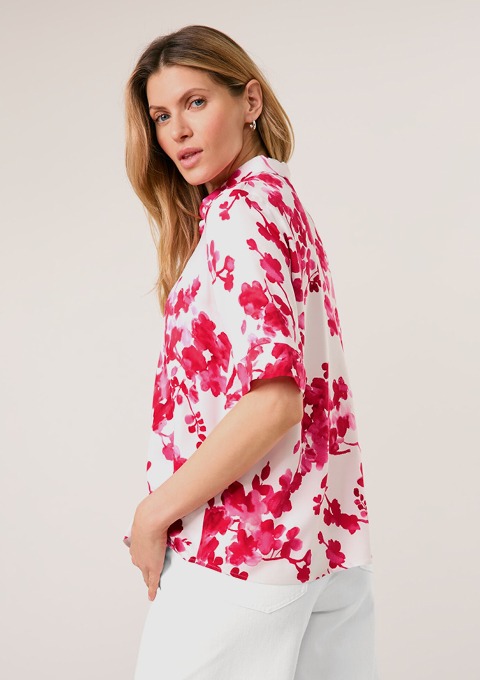Ein florales Hemd in Weiß und Pink mit bunten Blumenmustern. Ein florales Hemd in Weiß und Pink mit bunten Blumenmustern.