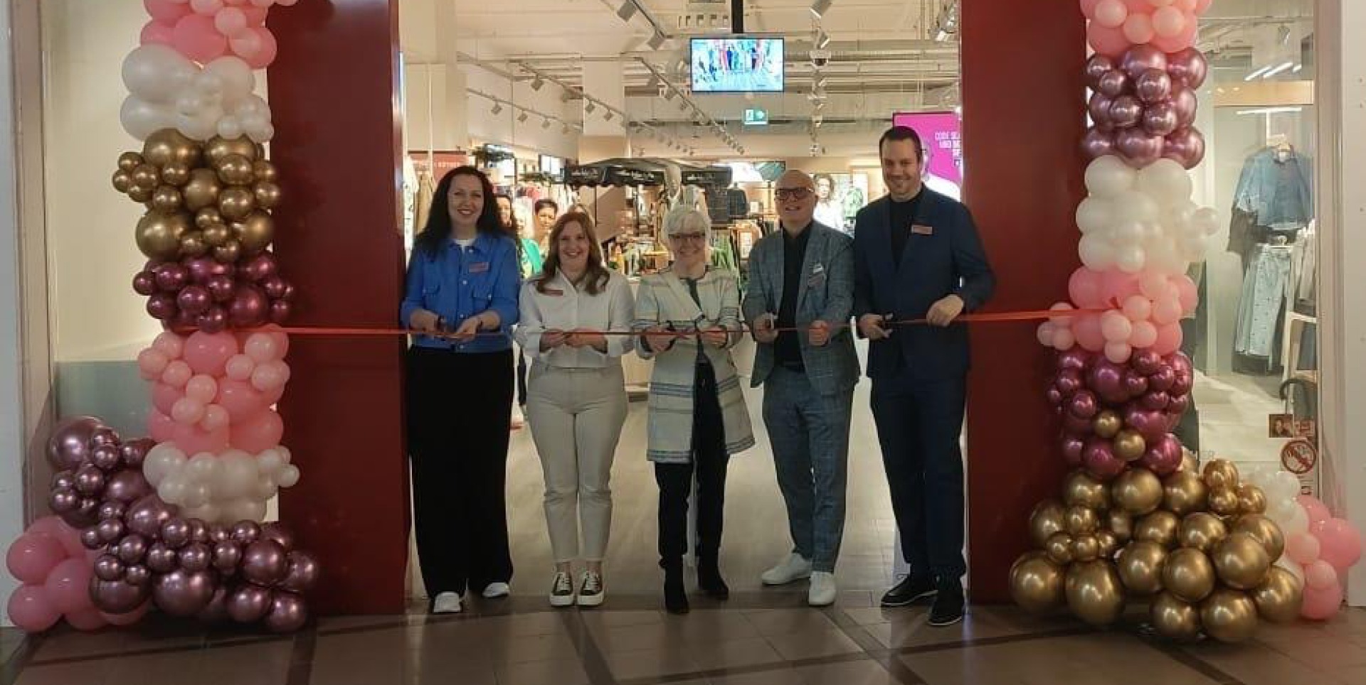 Eröffnung eines Geschäfts mit Personen, die ein Band schneiden, umgeben von bunten Luftballons. Das Team aus Kempten bei der Neueröffnung nach dem Umbau