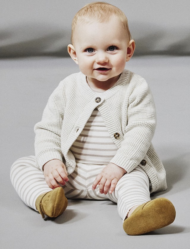 Ein Baby trägt einen gestreiften Pullover und braune Schuhe. Ein Baby trägt einen gestreiften Pullover und braune Schuhe.