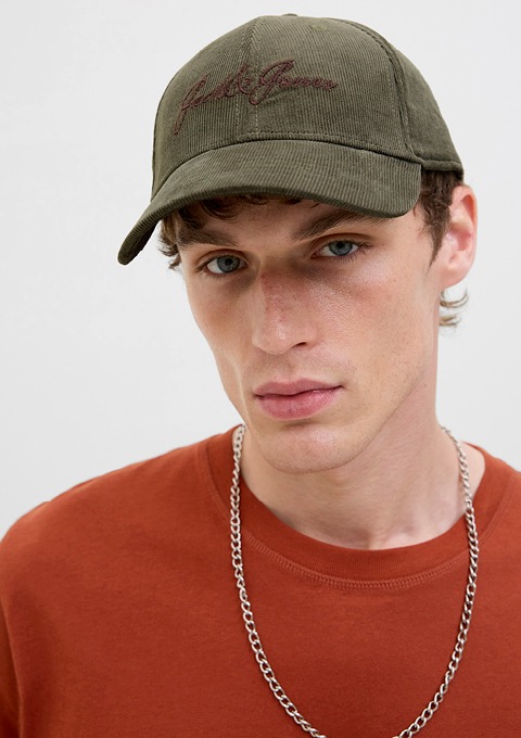 Ein junger Mann trägt eine grüne Baseballcap und ein orangefarbenes T-Shirt.