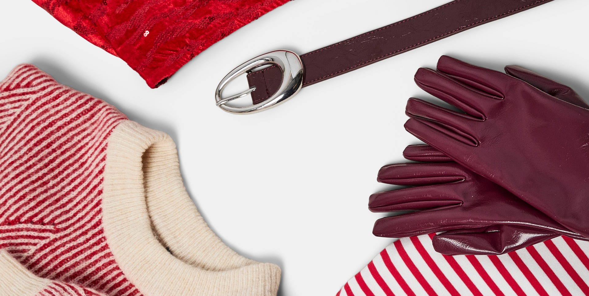 Rote Paillettenstoff, brauner Ledergürtel mit silberner Schnalle, rote Lederhandschuhe, rot-weiß gestreiftes Shirt und rot-weiß gestreifter Pullover mit cremefarbenem Kragen.