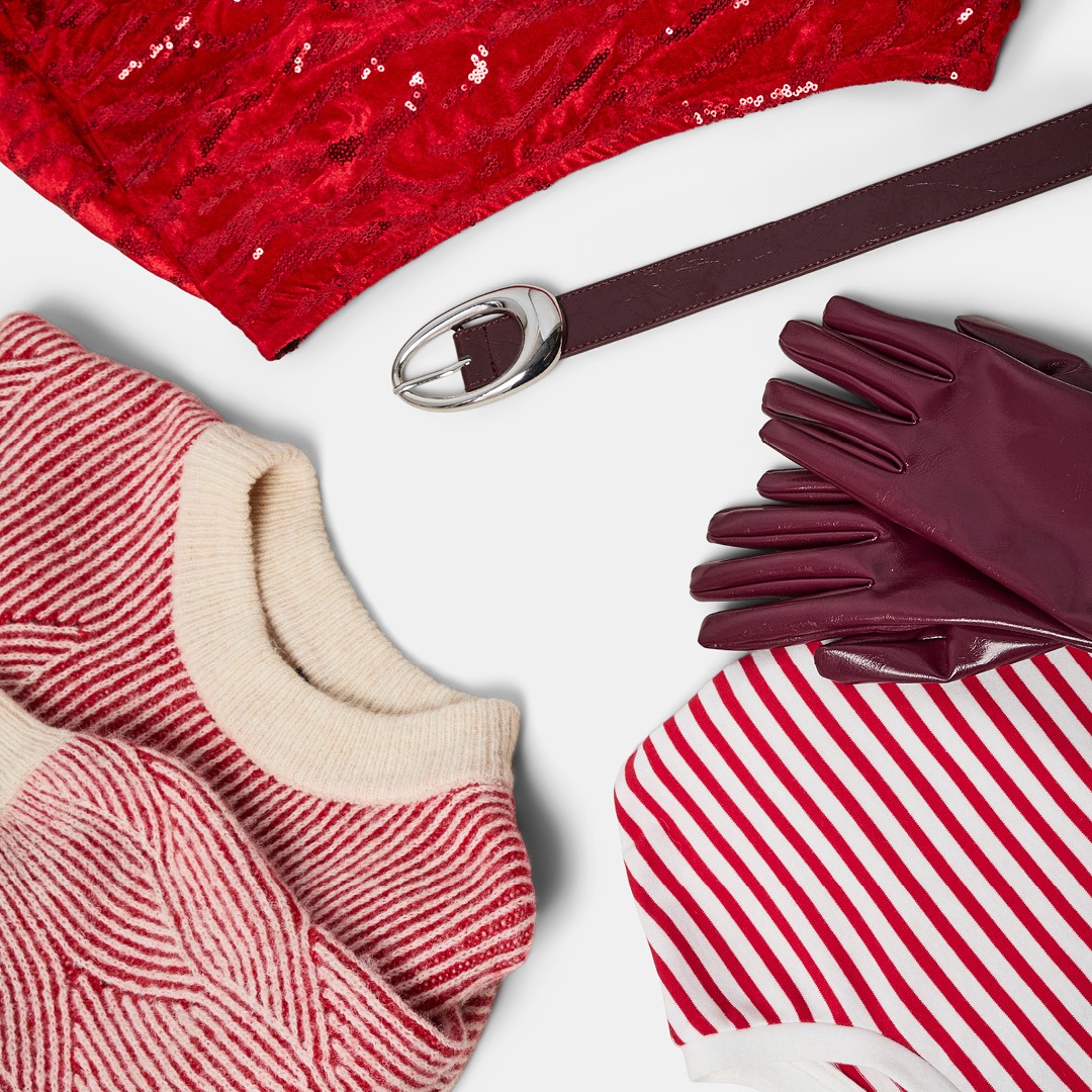 Rote Paillettenstoff, brauner Ledergürtel mit silberner Schnalle, rote Lederhandschuhe, rot-weiß gestreiftes Shirt und rot-weiß gestreifter Pullover mit cremefarbenem Kragen.