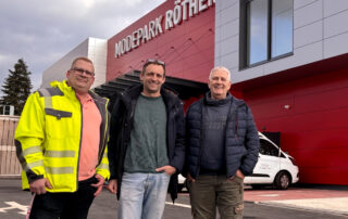 Drei Männer stehen vor einem Gebäude in Lohmar von Modepark Röther