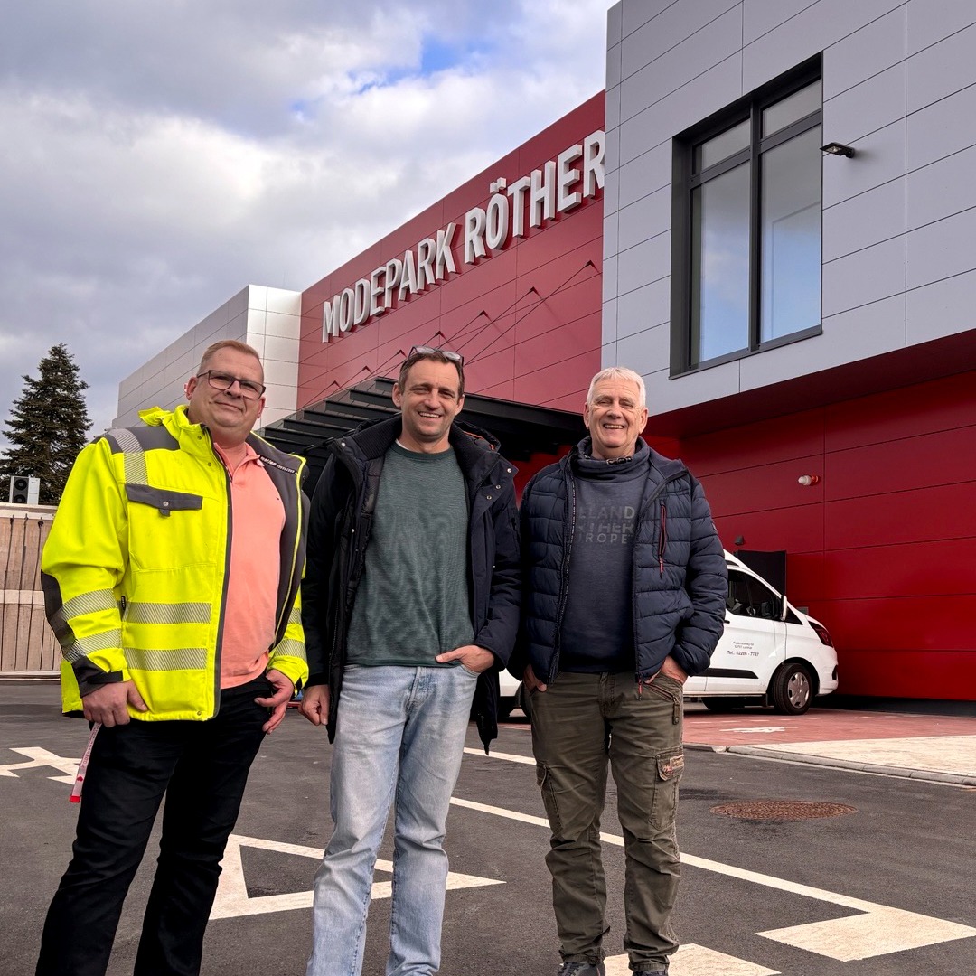 Drei Männer stehen vor einem Gebäude in Lohmar von Modepark Röther